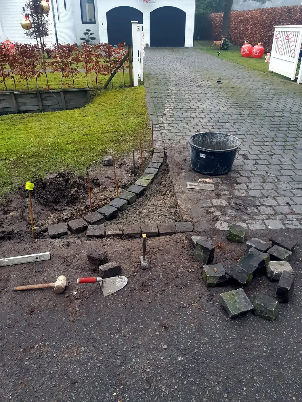 Kasseien van een oprit worden opnieuw gelegd met touw en uitzetpinnen