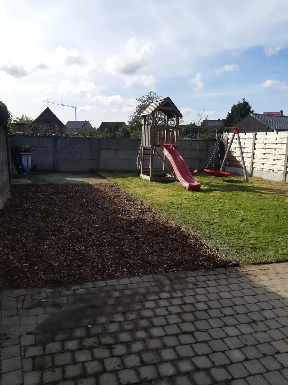 Tuin met speeltoren: gazon gemaaid en strook met verse houtsnippers