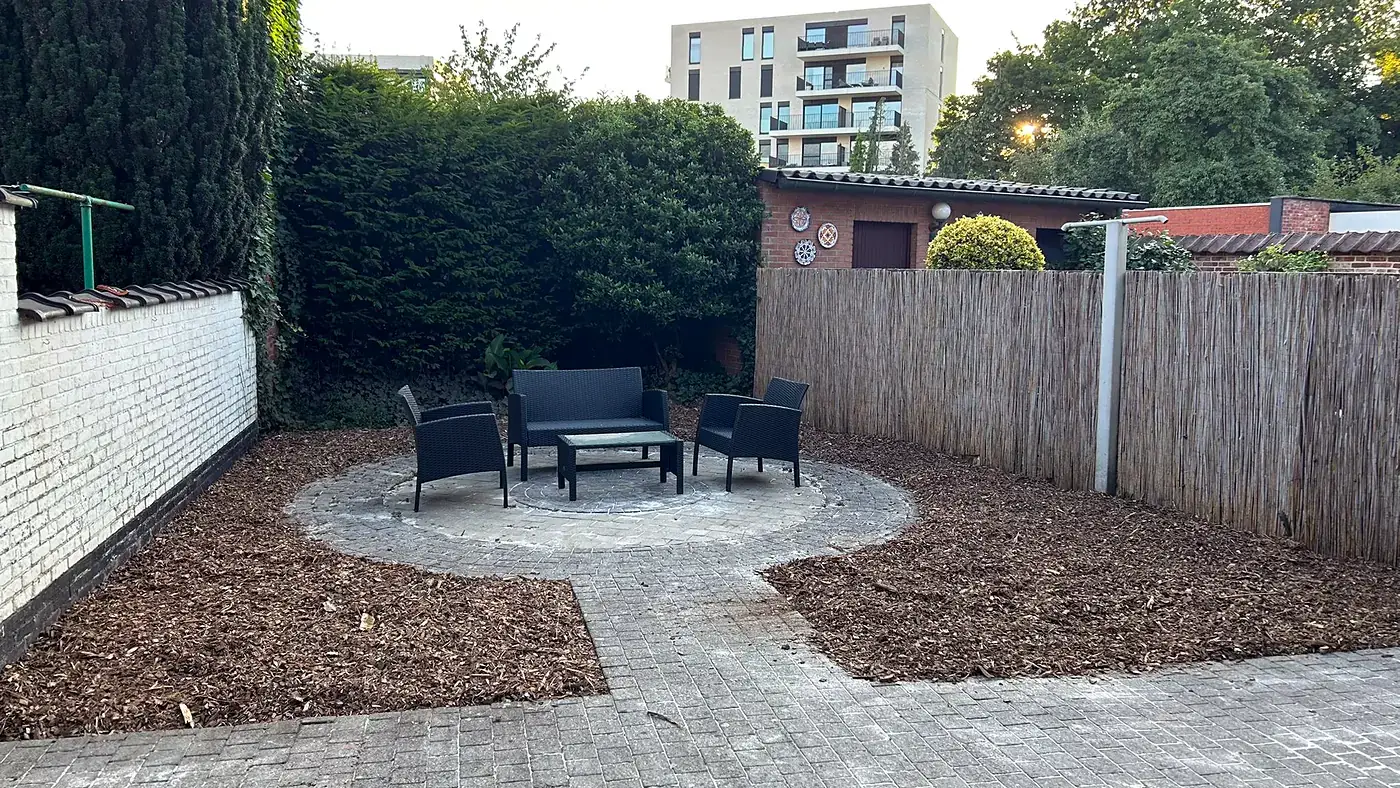 Opgeknapte stadstuin: rond terras met zitgroep en borders in houtsnippers